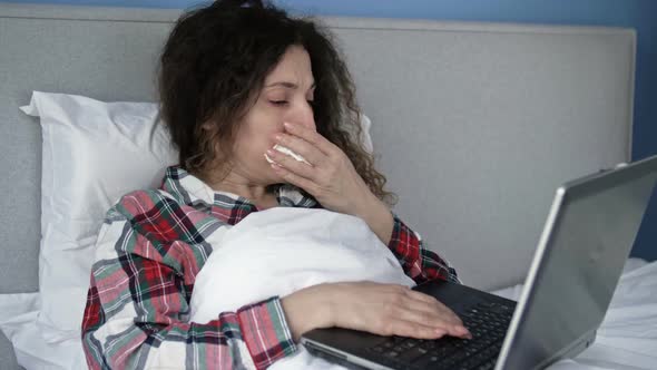 Sick Woman Lying in Bed with Laptop in Self Isolation