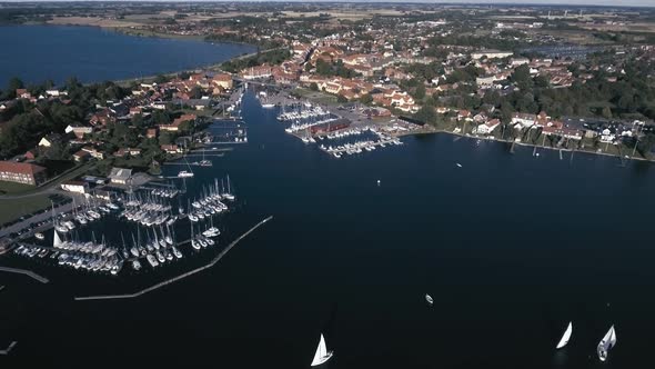 Flying High Up Over Harbor With Sailboats On The Water