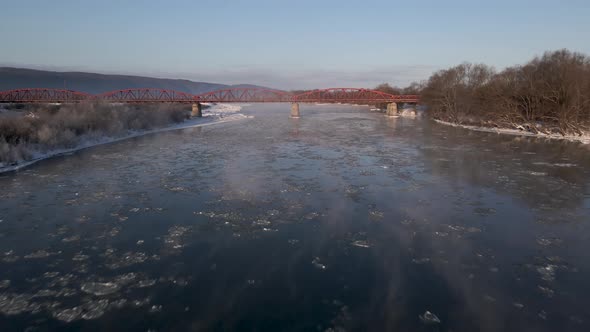 Drone Shot Flies Forward Over the Frozen River to the Red Steel Bridge Aerial View  Video Footage alt