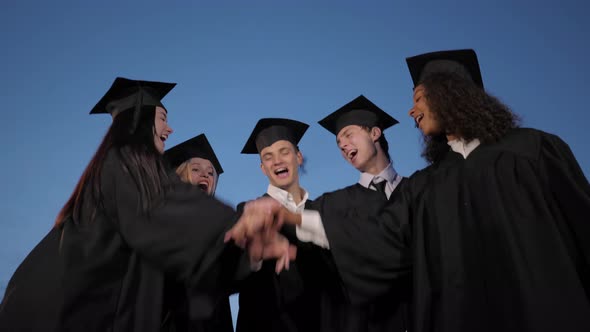 Happy Young Graduate Students Group Put Hands on One Another - Great Team. alt