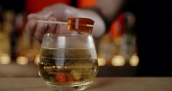 Bartender Adds Topping Marmelade on the Stick to the Cocktail Glass Making the Cocktail at the Bar alt