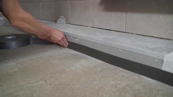 The Worker Glues the Floor Tape. Installation of Flooring. Damper Tape. alt