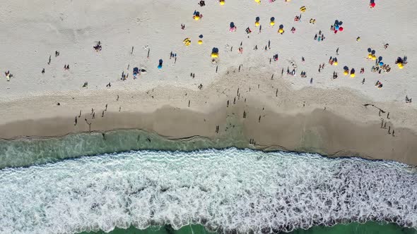 Top down view of beachgoers on large white beach