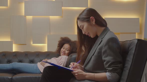 Asian Female Psychotherapist Counseling Black Little Girl with Mental Problems alt