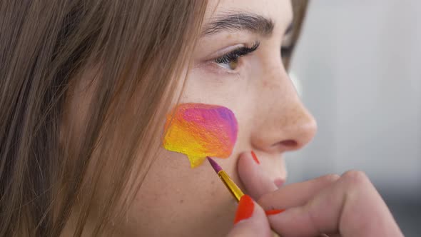 Close-up Portrait of Young Pleasant Woman. Artist Is Painting Multicolor Message Box on the Girl's alt