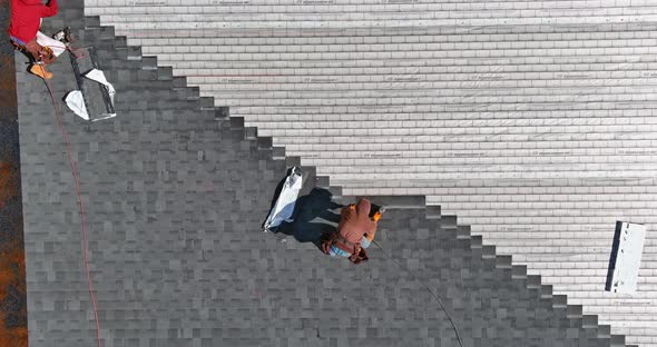 Roofer Hands Installing Asphalt Shingles on House Construction Roof with Hammer and Nails alt