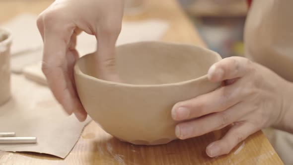 Hands of Female Potter Smoothing Inner Surface of Handmade Clay Bowl alt