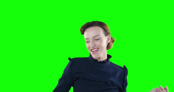 Happy Caucasian woman dancing on green background.