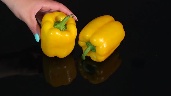 Two Ripe Juicy Yellow Peppers on a Black Mirror Background alt