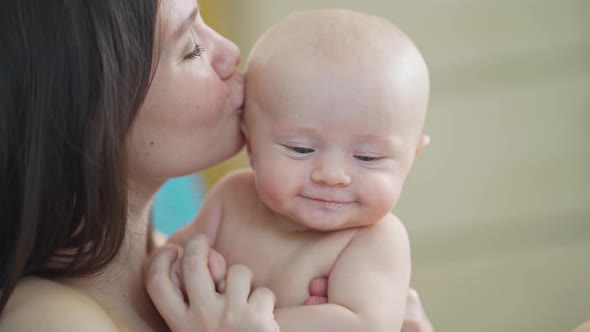a Beautiful and Gentle Mother Kisses a Baby alt