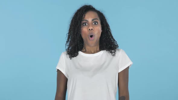 Shocked African Girl Isolated on Blue Background Wondering alt