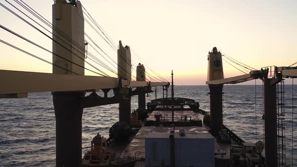 Slowmotion View of Bulk Carrier Deck Sailing Into Sunset During Ocean Transportation alt