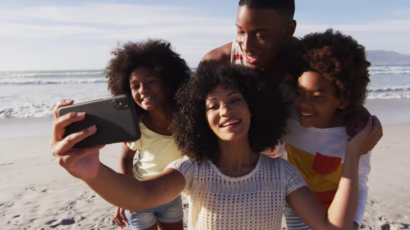 African american parents and their children taking a selfie with smartphone on the beach alt