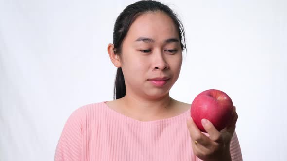 Asian woman holding an apple with a bite and smile showing strong teeth alt