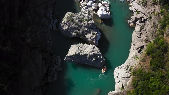 rafting boat going down the rapids on river in rocky valley. Overhead Shot alt