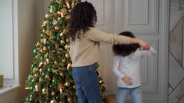 Young Mother Dances with Her Little Daughter on the Background of a Christmas Tree, Stock Footage->