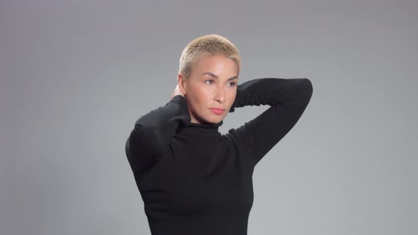 Blonde with Short Haircut in Studio Poses for Camera on Grey Ideal Skin alt