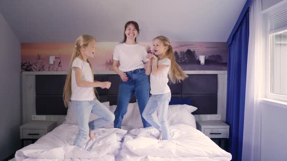 Mother and Daughters Jumping on Bed