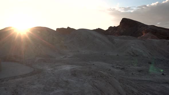 Sun shining behind compacted sand dunes in Death Valley, California, Aerial approach shot alt