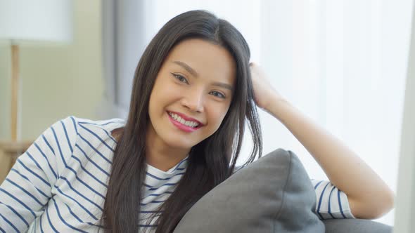 Portrait of Asian beautiful woman sit on sofa in living room at home. alt