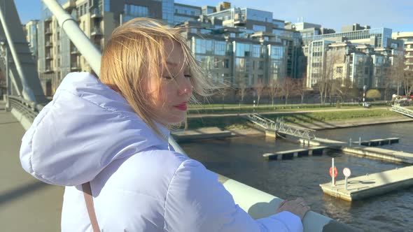 Attractive Blonde Woman Stands on the Bridge Closeup Portrait Embarrassed Look