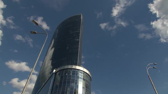Mirrored Skyscraper on a Background of Flying Clouds alt