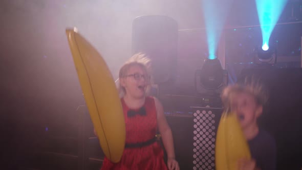 Two Young Girls at a Children's Party / Disco Playing with Blow Up Bananas alt