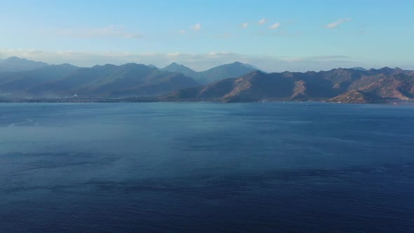 High mountains of volcanic islands in Indonesia surrounded by deep blue sea, clear bright blue sky alt