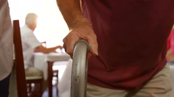 Mid section of doctor assisting a senior man to walk with walking frame alt