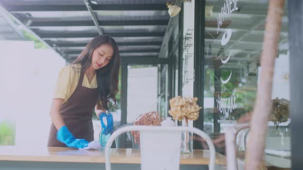 Close-up.Asian female worker clean the table is disinfected by sprinkling alt