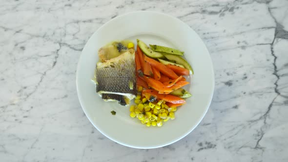 A piece of fried fish fillet and vegetables on a rotating plate. 