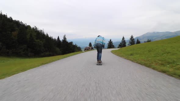 A man downhill skateboarding on a mountain road alt