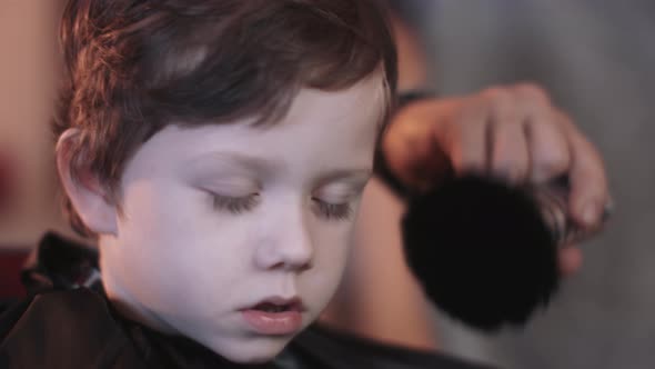 Hairdresser cutting hair of child in Barbershop