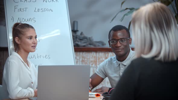 White Woman and Black Man Having an English Lesson and Talking with Their Woman Teacher alt