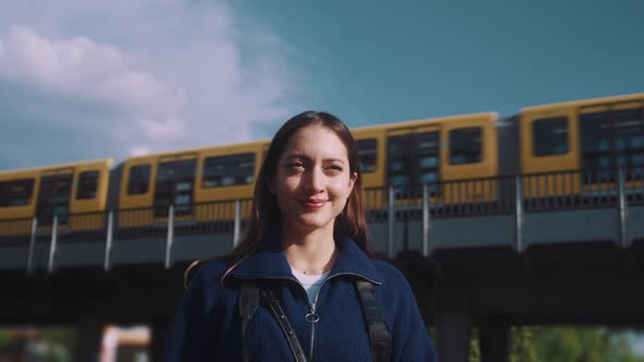 Young woman takes picures wih camera with train moving in the background alt