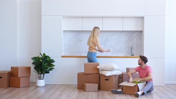Young woman blonde with long loose hair helps bearded man unpack brown cardboard alt
