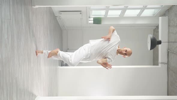Young Man Performs Elements of Modern Dance From a White Studio