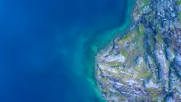 Blue Water at the foot hills of a rocky mountain, Aerial view alt