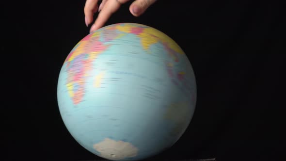 Geographical Globe is Twisted Around Its Axis By a Female Hand alt