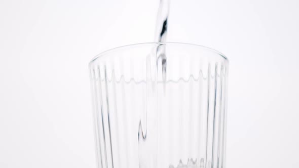 Pure water pouring into glass on white background.
