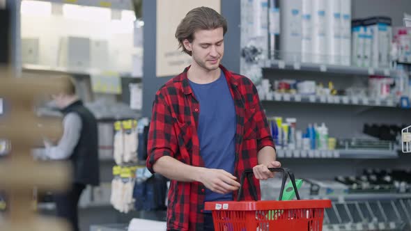 Middle Shot Portrait of Young Caucasian Confident Man Putting Tool in Shopping Basket Looking at alt