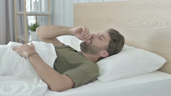 Sick Young Man Coughing While Having Nap in Bed alt