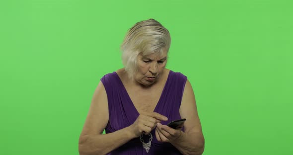 An Elderly Woman Works on a Smartphone. Old Grandmother Smiles. Chroma Key alt