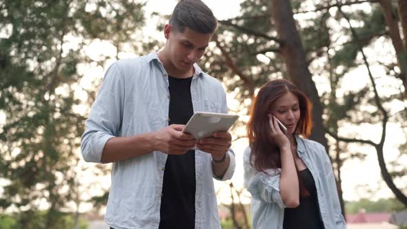 Focused Handsome Boyfriend Searching Route Direction Online As Girlfriend Talking on Phone Smiling alt