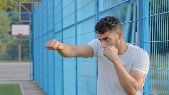 Serious Focused Young Arabic Hispanic Male Athlete Boxer Waving Hands with Clenched Fists Showing alt