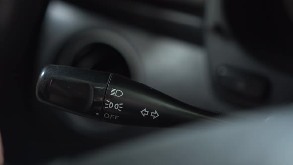 A Man Turns on the Turn Signal to the Left on the Lever in the Car alt
