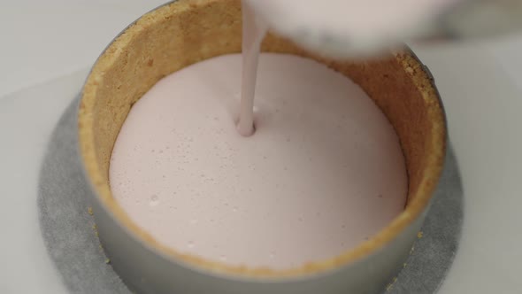 Pouring cheese ingredient into shortcrust pastry. Cheesecake cooking process in slow motion.