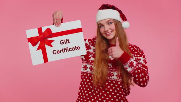 Adult Girl Wears Red New Year Sweater and Hat Presenting Card Gift Certificate Coupon Winner Voucher alt