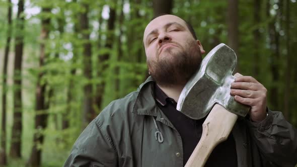 Slow Motion Of Casual Strong Man Has Shave with Ax in Wild Deciduous Forest. alt
