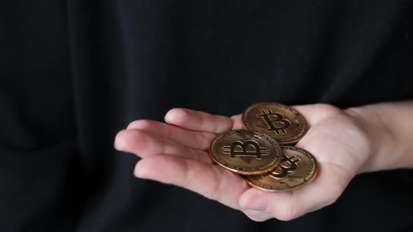 Bitcoin golden coins falling in female hand, close up